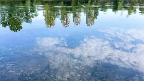 City Buildings Reflected in Calm River Water with Blue Sky and Clouds Stock Footage 331608236