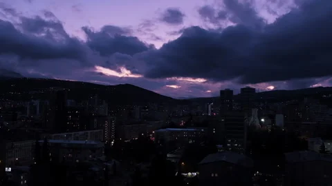 City buildings under dramatic dark blue purple evening sky with clouds Stock Footage 236695776