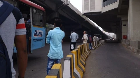 A city bus approaches a intersection while people wait at the bus stop in India Video stock 83458927