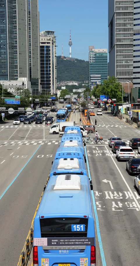 City buses queueing before intersection, overhead view, N Seoul Tower on back Stock Footage 295053782