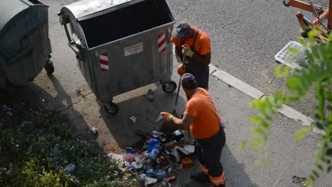 City cleaners empty garbage cans on the street into a garbage truck Stock Footage 196995488