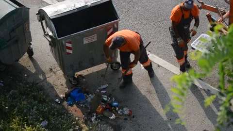 City cleaners empty garbage cans on the street into a garbage truck Stock Footage 196995597
