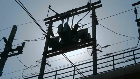 City electric transformer above the ground on two pillars against a blue sky Stock Footage