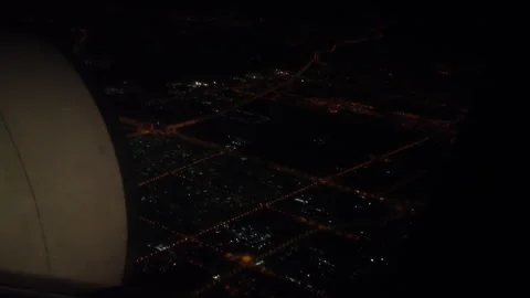 City lights form glowing grids beneath the wing of a plane during a quiet night Stock Footage 313341592