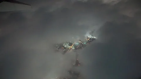 City lights through a gap in clouds at night from an airplane Video stock 347984405