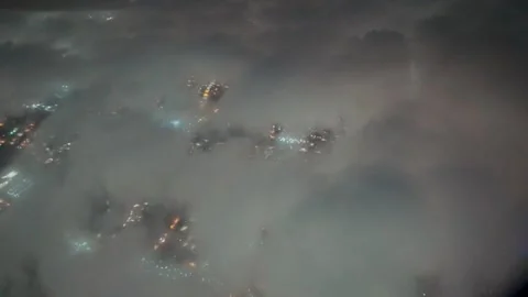 City lights through low clouds on night approach from an airplane Vídeos de archivo 348050858