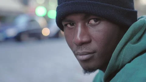  City Reflection: Black Man Sits Thoughtfully on Sidewalk Amid Urban Traffic  Video stock 265858046