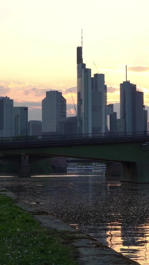 City Skyline and Bridge Reflected in River at Sunset With People Crossing Stock Footage 334945993