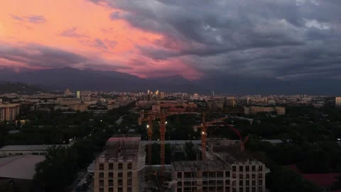 City skyline at sunset with construction cranes and dramatic clouds Stock Footage 339124155