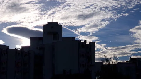 City skyline under dramatic sky. Silhouettes of tall buildings against clouds in Stock Footage 218993056