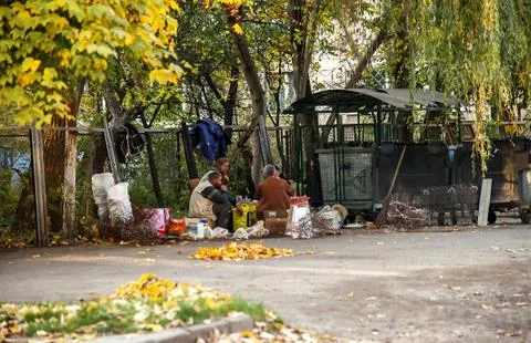 City street with trash bins and homeless people on picnic Stock Photos