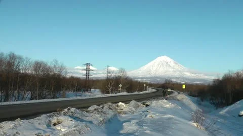The city, winter, cold, the man walks with a dog against a huge volcano Видео 11909577