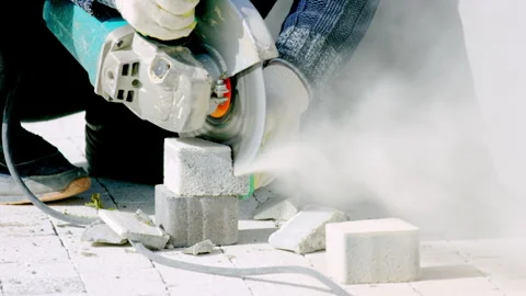 City worker cuts off side of paving slab carefully in park Stock Footage 244787442