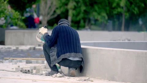 City worker uses angle grinder to cut paving slabs Stock Footage 246054014