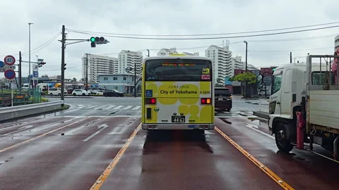 City of Yokohama bus at wet intersection with traffic lights and urban Japan Stock Footage 333013003