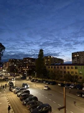 Cityscape captured at twilight featuring illuminated buildings and cloudy sky Stock Photos