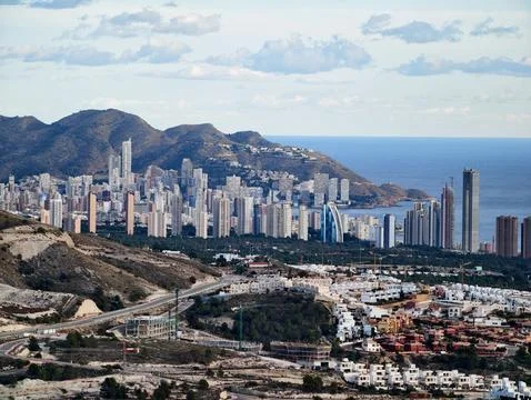 Cityscape with mountains and water, Vertical city growth rising against rocky Stock Photos