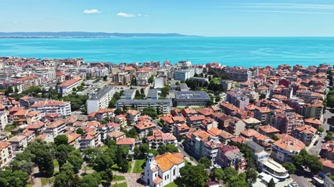 Cityscape with red rooftops, green parks, and blue sea under a clear sky during 動画素材 337901205