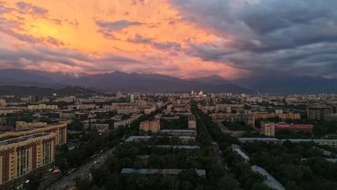 Cityscape at sunset with mountains and dramatic clouds in background 写真素材