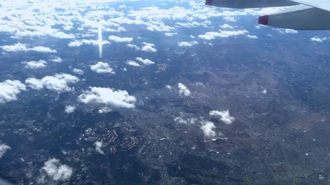Cityscape through airplane window, clouds casting shadows on landscape, sunny da Stock Footage 267340263