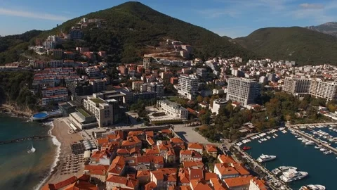 Cityscape with towering mountain in background, surrounded by trees and water Stock Footage 268710989