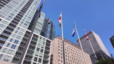 Cityscape view of flags waving in the breeze with modern skyscrapers and blue Stock Footage 326980285