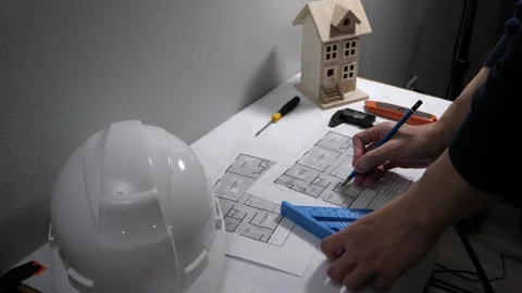 Civil engineer architech writing reading blueprints and looking at scale model Stock Footage 258423095