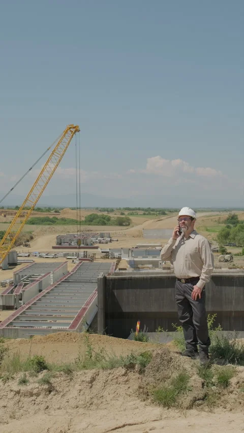 Civil engineer in hard hat talking on phone at highway viaduct construction.. Stock Footage 338008933