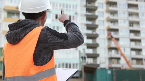 Civil engineer looking drawing of a tall building on the construction site Stock Footage 117989484