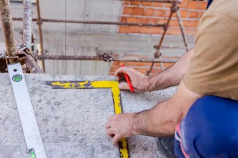 Civil engineer is marking point with pencil on concrete at building site Stock Photos