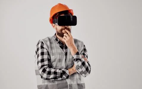 Civil engineer wearing 3D virtual reality glasses and an orange hard hat on his Stock Photos