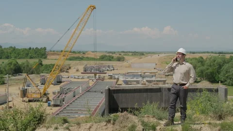 Civil Engineer In White Hard Hat Talking On Mobile Phone Reporting Project .. Stock Footage 337707044