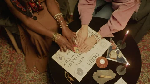 Clairvoyant and Female Client Tracing Letters on Ouija Board Stock Footage 247641490