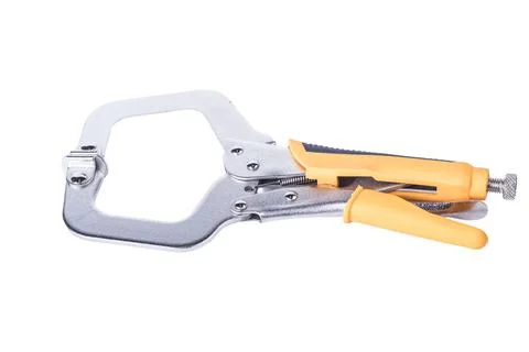 A clamp is placed on a white surface. It features a metal frame with orange r Foto stock