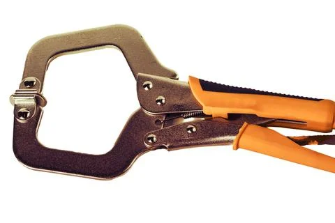 A clamp is placed on a white surface. It features a metal frame with orange r Stock Photos