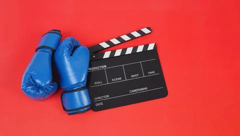 Clapper board and blue boxing gloves on red  background Stock Photos