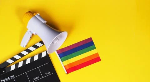 Clapper board and rainbow pride flag and megaphone on yellow background. Stock Photos