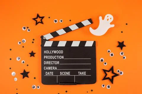 Clapper board in spider webs, spiders, ghost, eyes on orange background. Stock Photos