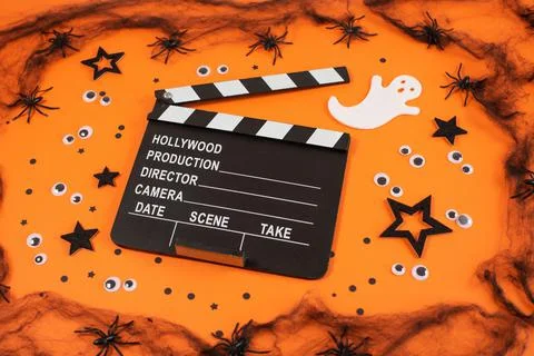 Clapper board in spider webs, spiders, ghost, eyes on orange background. Stock Photos