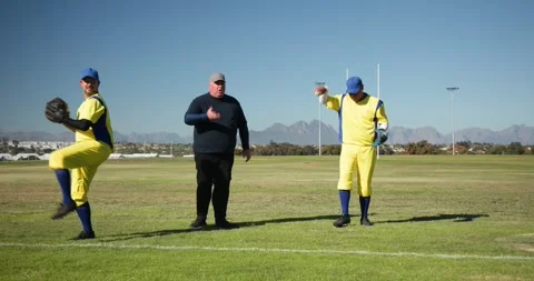 Clapping baseball coach guiding players practicing throws on field, with gloves Stock Footage 343512860