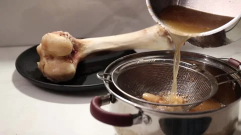 Clarifying Bone Broth: Straining Through a Sieve to Separate Clear Stock Stock Footage 344031850