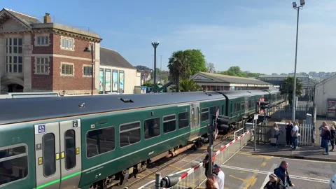 Class 58 diesel commuter train passing the level crossing at Paignton Stock Footage 308409210