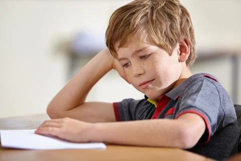 Class, notebook and bored child at desk, learning and education with school exam Stock Photos
