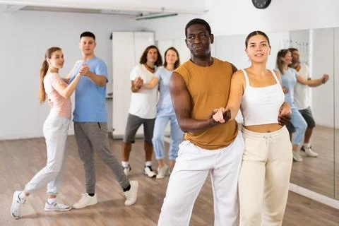 Class of positive multinational couples enjoing partner pair dancing during Fotos Stock
