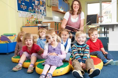 Class Of Pre School Children At Story Time With Teacher Stock Photos