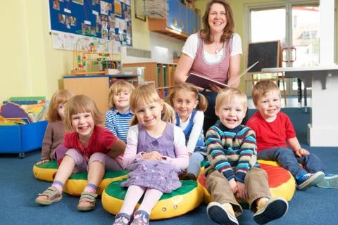 Class Of Pre School Children At Story Time With Teacher Stock Photos