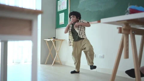 In class, The teacher and students sing together, and the boys dance happily Stock Footage 282878985