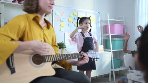 In class, The teacher and students sing together, and the boys dance happily Stock Footage 285320469