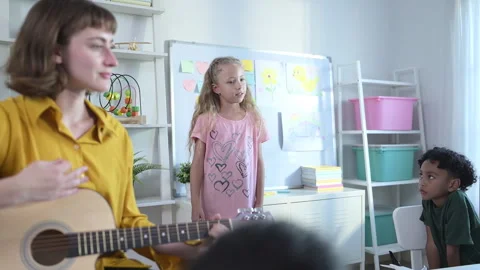 In class, The teacher and students sing together, and the boys dance happily Stock Footage 285325413