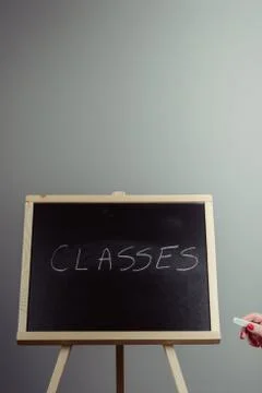 Classes written in white chalk on a black chalkboard Stock Photos
